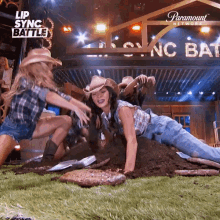 a woman in a cowboy hat is doing push ups in the dirt ..