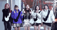 a group of girls are standing next to each other wearing fur coats and jackets .