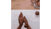 a person is rolling a ball of cookie dough on a cutting board