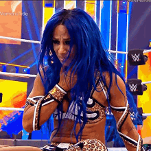 a woman with blue hair is sitting in a wrestling ring wearing a leopard print outfit