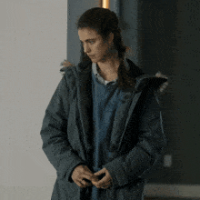 a woman wearing a parka with a fur hood and a blue shirt