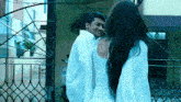 a man and a woman are standing next to each other in front of a gate