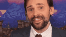 a man with a beard in a suit and tie is smiling