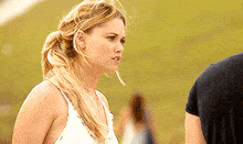 a woman in a white tank top stands next to a man in a black shirt