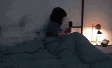 a woman sits on a bed with a microphone in her hand