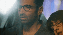 a man wearing glasses is sitting next to a woman wearing glasses