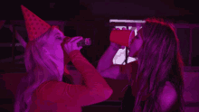 a woman in a party hat drinks from a red cup