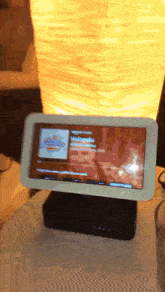 a tablet with a picture of a man on it is sitting on a table next to a lamp