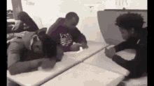 a group of young men are sitting at tables in a classroom .