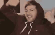 a man in a hoodie is giving a thumbs up .