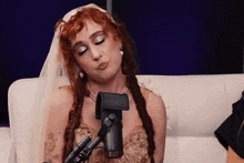 a woman with red hair is sitting on a couch with a microphone in front of her .