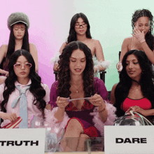 a group of women sitting around a table with a sign that says truth and dare