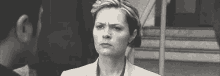 a black and white photo of a woman in a suit making a funny face .