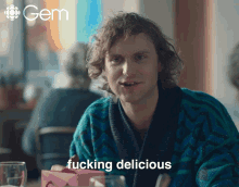 a man sitting at a table with the word fucking delicious on the bottom