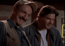 two men are laughing together in front of a neon sign