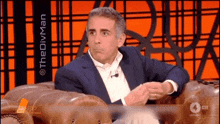 a man in a suit is sitting in a chair with the divman written on the screen