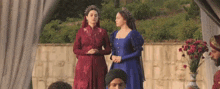 two women in medieval dresses are standing next to each other in front of a man in a turban .
