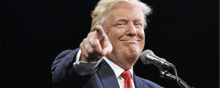 donald trump is smiling while pointing at the camera