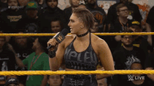 a woman in a wrestling ring speaking into a microphone with the words wwe on the screen behind her