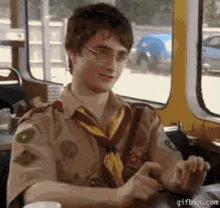 a boy scout is sitting at a table with a cup of coffee