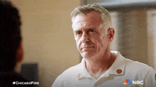 a man wearing a white shirt with a red button that says ' chicago fire ' on it