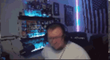 a man wearing headphones is playing a video game in a room with an american flag in the background .