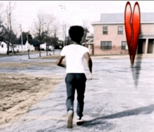 a man in a white shirt is running down a street with a red heart in the background