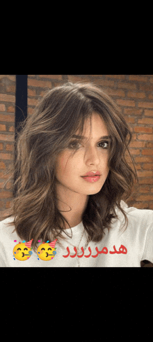 a woman with brown hair is wearing a white t-shirt with arabic writing on it