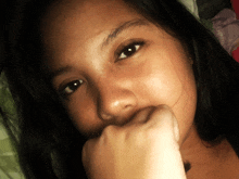 a woman covering her mouth with her hand while looking at the camera
