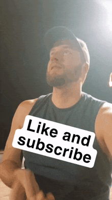 a man wearing a hat and a black tank top with the words like and subscribe on it