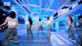 a group of women are dancing on a stage with a kpop logo in the corner