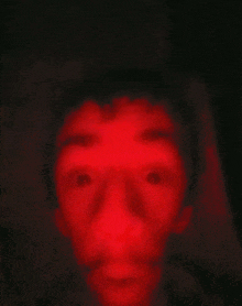 a close up of a person 's face with a red light behind it .