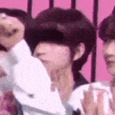 a group of people are standing next to each other in front of a pink background .