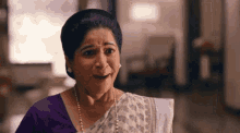 a woman in a purple top and white saree is making a face