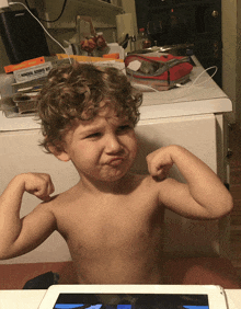 a young boy flexes his muscles in front of a bose speaker and a mineral science kit