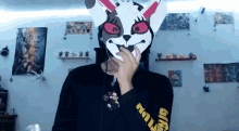 a person wearing a bunny mask and a black shirt is covering their mouth .