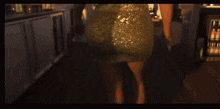 a woman in a gold sequined dress is walking