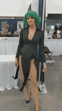 a woman in a green wig and a black dress stands in front of a sign that says comic con