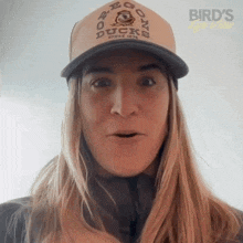 a woman wearing an oregon ducks hat makes a surprised face