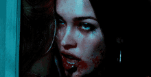 a close up of a woman with blood on her face in a dark room .