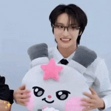 a man in glasses is holding a stuffed animal with a pink star on its head .