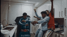 a group of young men are dancing in a kitchen with a bag that says big boys