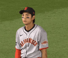 a man in a san francisco giants jersey stands on a baseball field