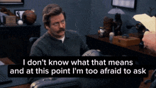 a man with a mustache sits at a desk and says " i don 't know what that means