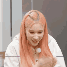 a woman with pink hair is smiling and holding a marshmallow in her hand