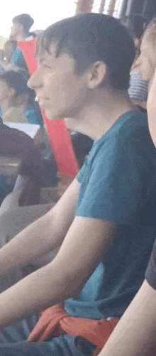 a man in a blue shirt is sitting in a crowd of people watching a game .