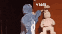 a person in a blue hoodie is standing in front of a statue with chinese characters on it