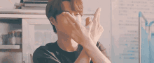 a young man is covering his face with his hands and making a funny face .