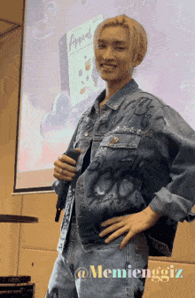 a man in a denim jacket is holding a microphone in front of a projector screen that says appeal