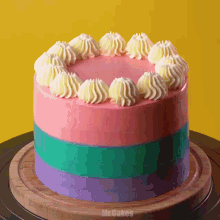 a cake with pink green and purple frosting is on a wooden cutting board